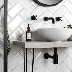 Metro white wall tile in gloss tiled on a bathroom wall in herringbone style.